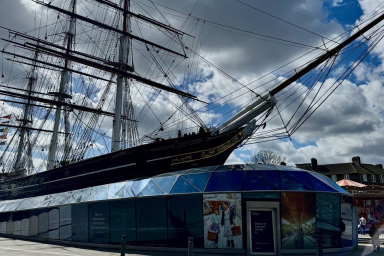 Cutty Sark -purjelaiva Greenwichissä, keulassa laivan nimi ja taustalla lasikatos